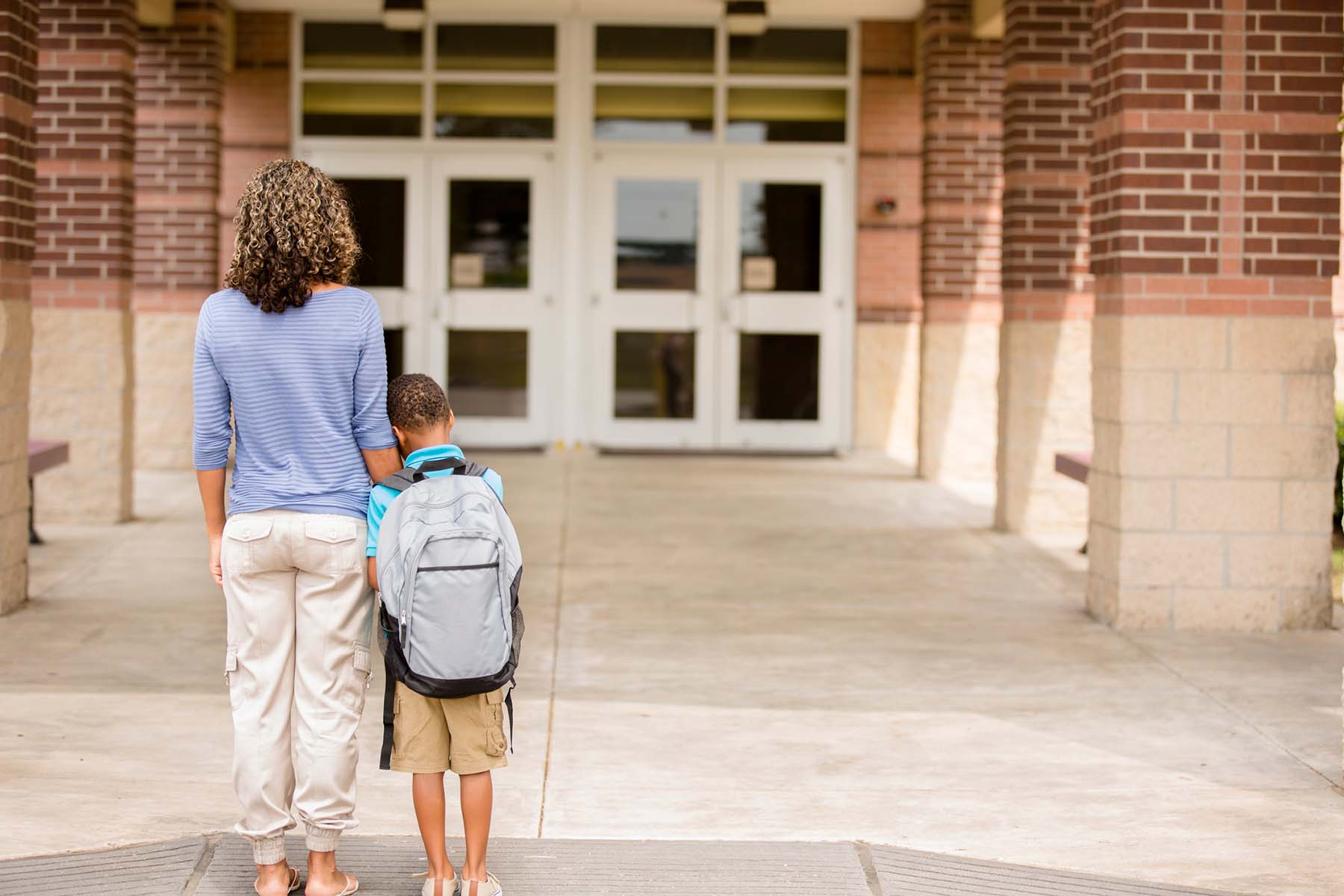 first day of school nervous boy holds on to mom